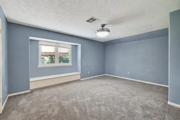 an empty room with windows and ceiling fan