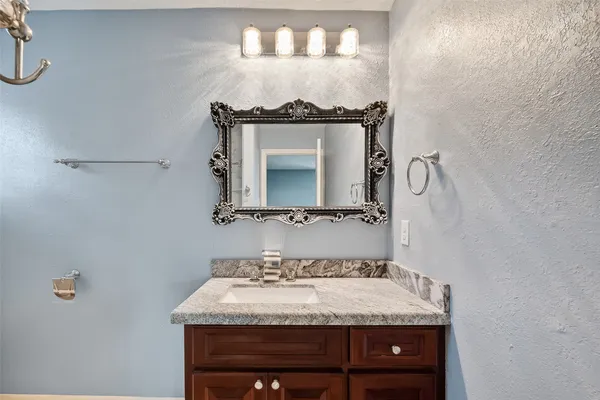 a bathroom with a granite countertop sink and a mirror