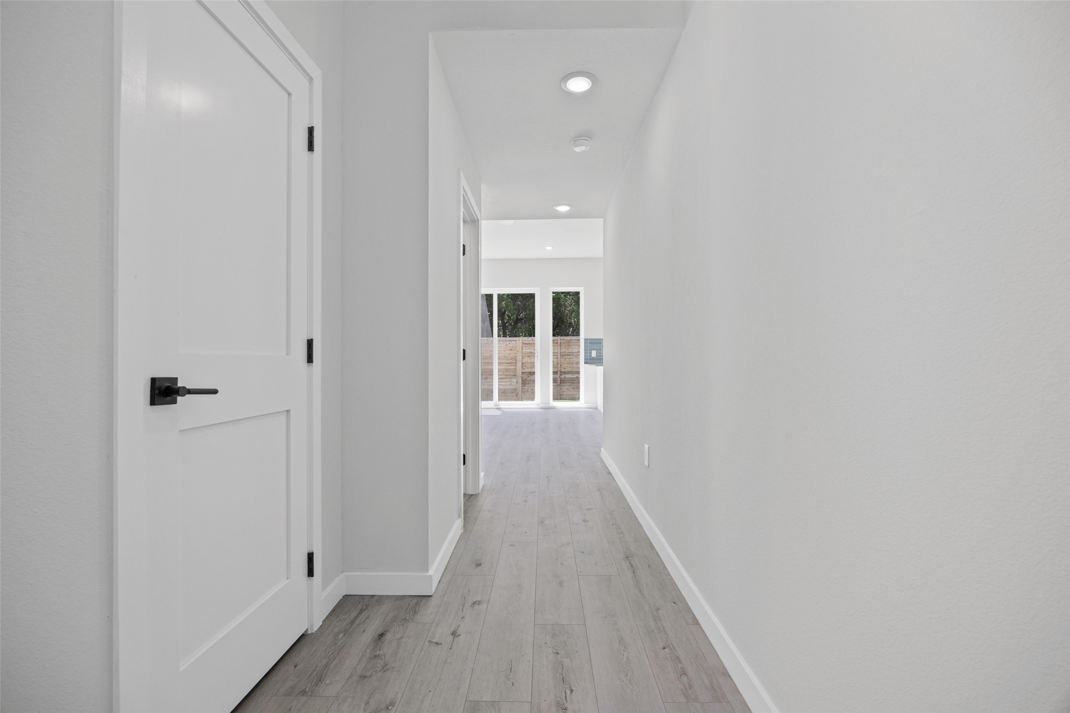 2000 Riverside Farms Road, Unit 5102 Austin, TX 78741 - Photo 3 of 25 A well-lit hallway with modern recessed lighting and durable wood flooring leads to a glass-paneled doorway.