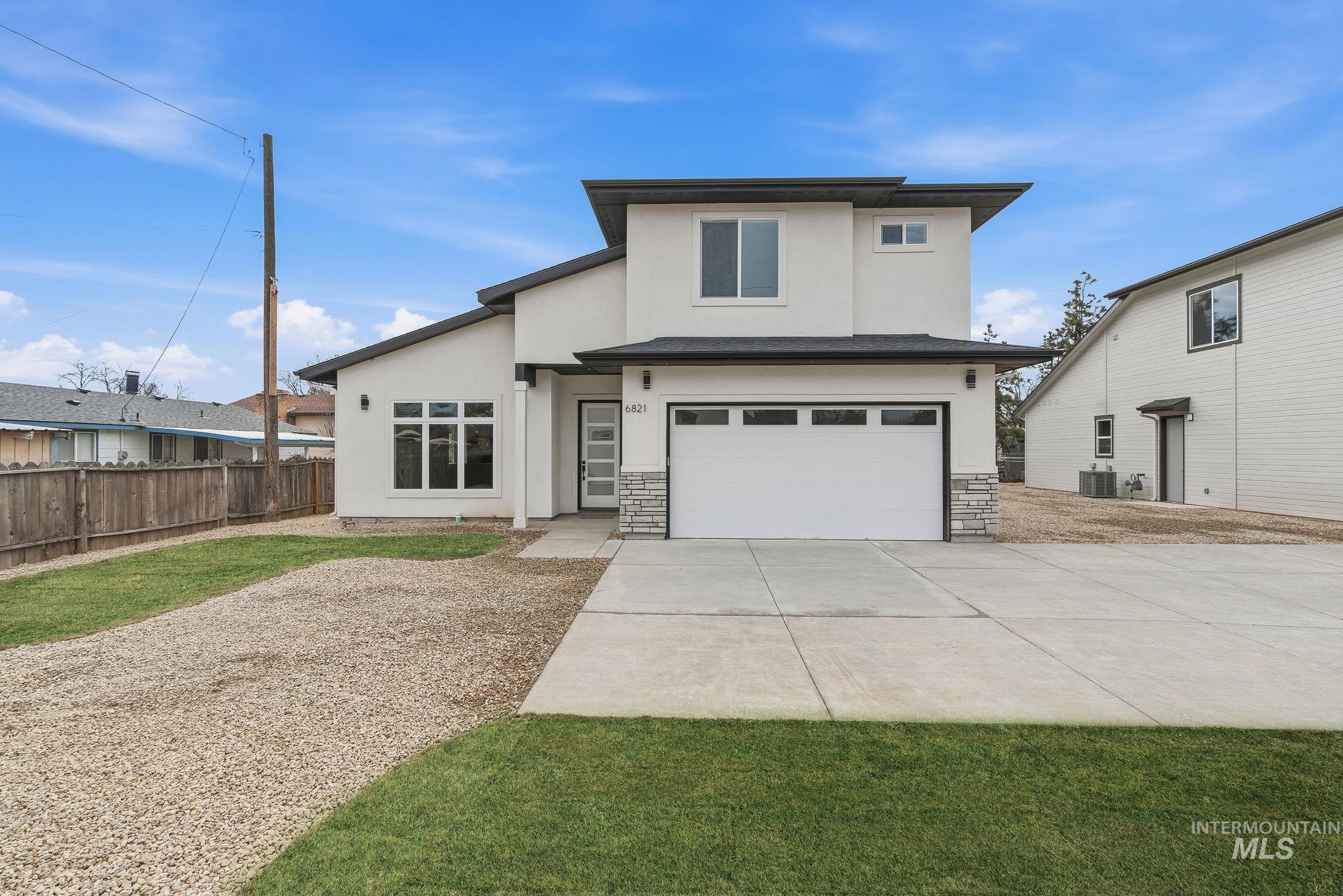 6821 West Ustick Road Boise, ID 83704 - Photo 2 of 42 View of front of home with a garage, stucco siding, concrete driveway, and stone siding