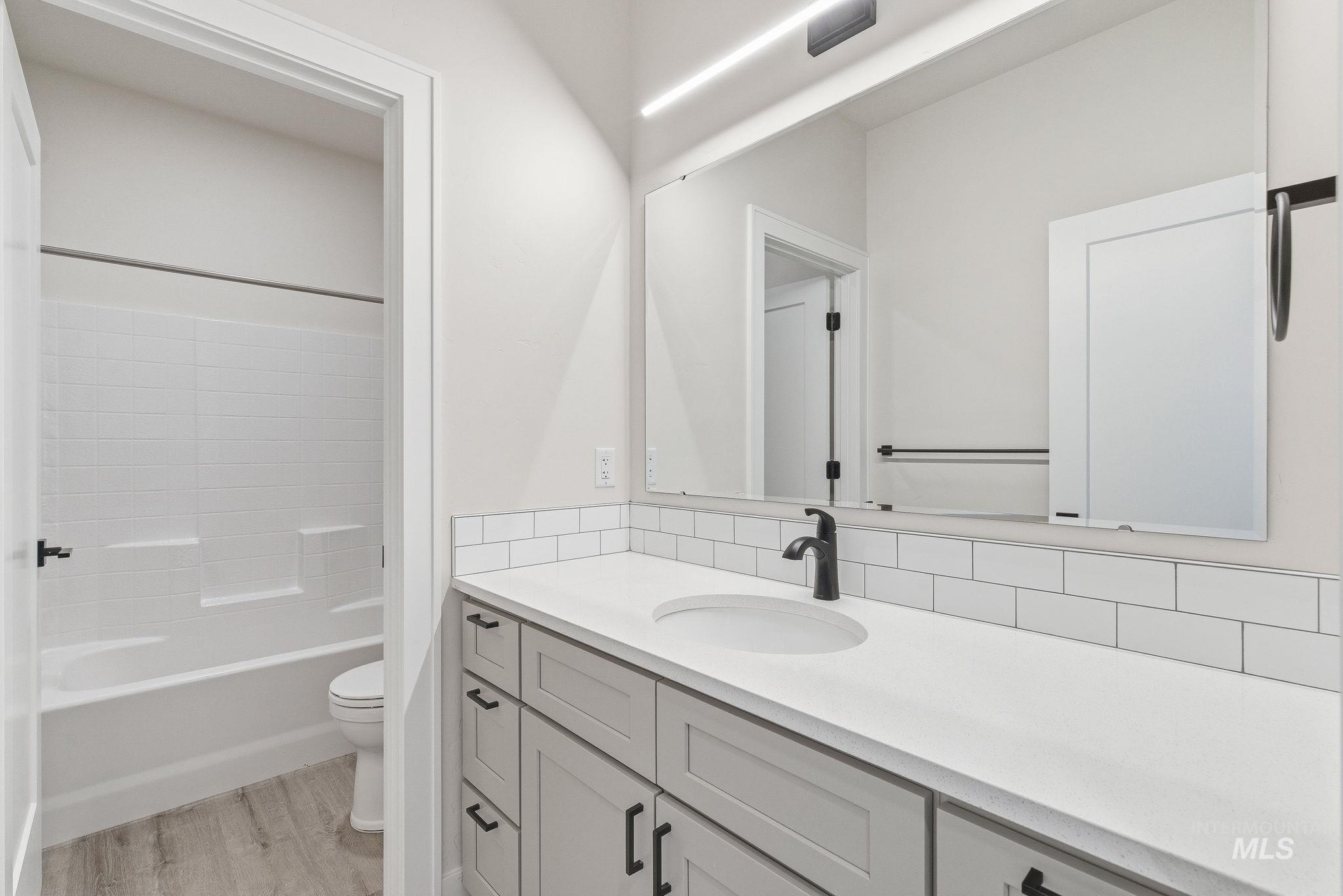 6821 West Ustick Road Boise, ID 83704 - Photo 36 of 42 Bathroom featuring vanity, light wood-style flooring, and bathtub / shower combination