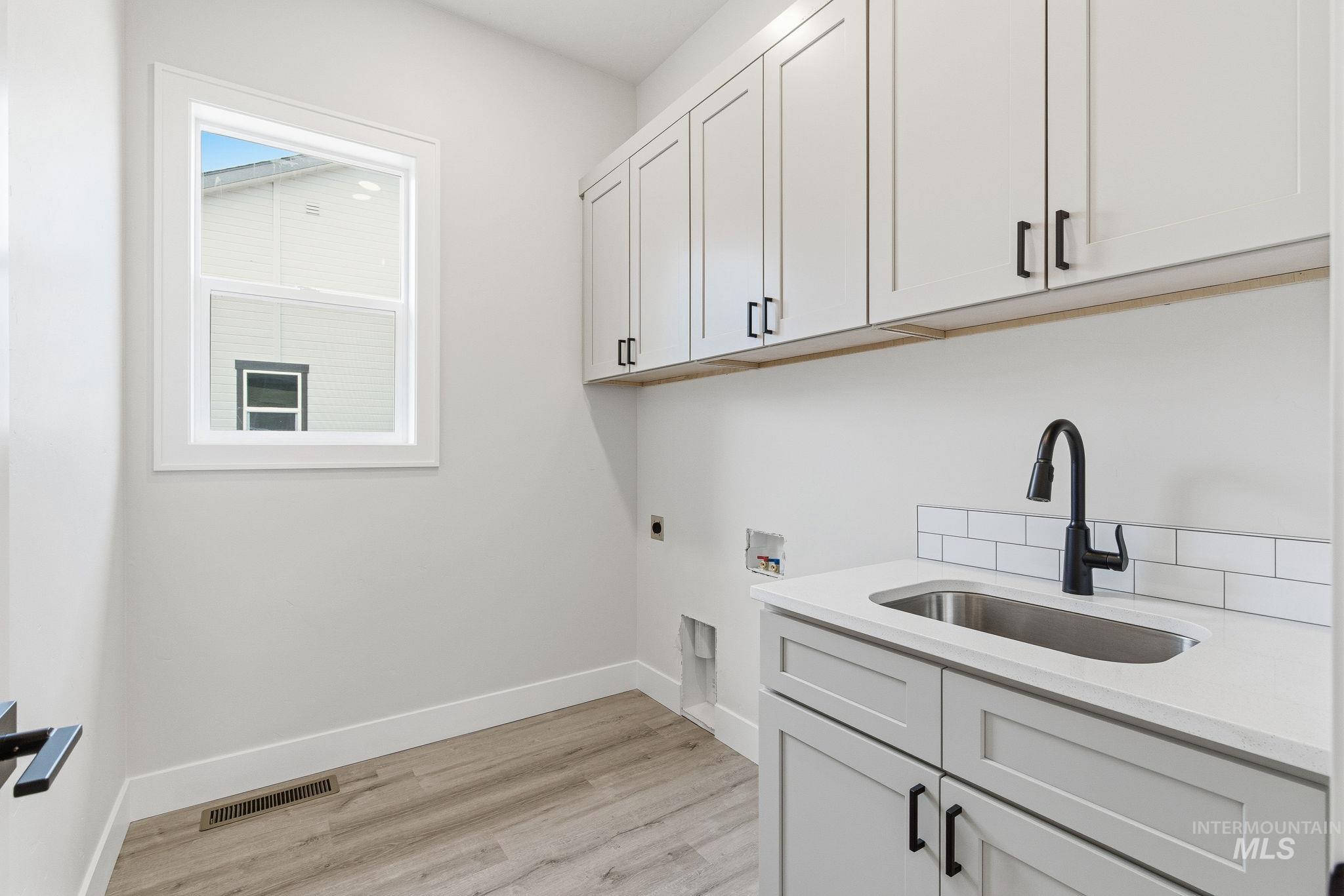 6821 West Ustick Road Boise, ID 83704 - Photo 38 of 42 Laundry area featuring cabinet space, light wood finished floors, electric dryer hookup, and hookup for a washing machine
