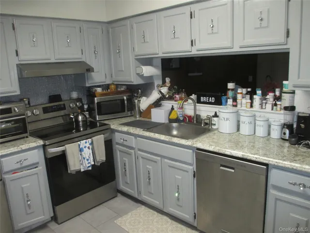 a kitchen with granite countertop white cabinets and stainless steel appliances
