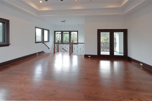 a view of empty room with wooden floor and fan