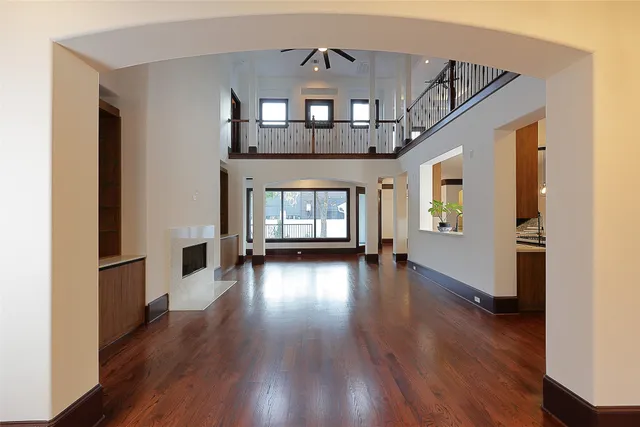 a view of a livingroom with wooden floor a ceiling fan and windows