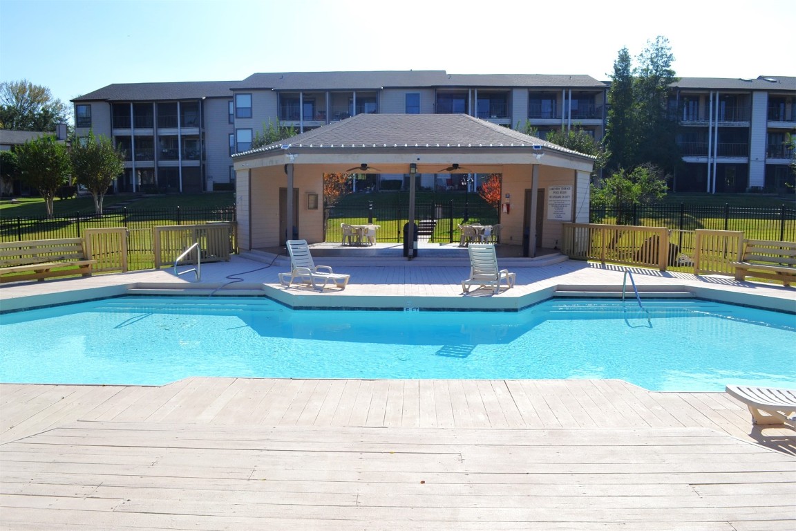 102 Lakeview Terrace, Unit D Conroe, TX 77356 - Photo 22 of 42 a view of pool with lawn chairs and floor to ceiling window