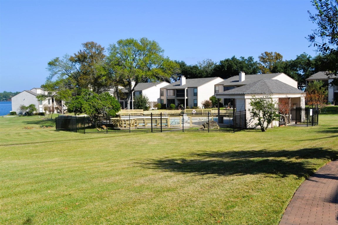 102 Lakeview Terrace, Unit D Conroe, TX 77356 - Photo 34 of 42 a front view of a house with a garden and swimming pool