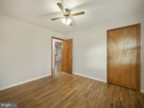 an empty room with wooden floor and fan