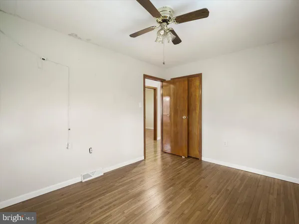 an empty room with wooden floor fan and windows