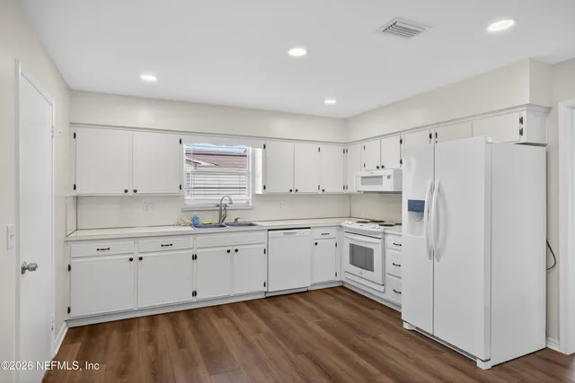 a kitchen with granite countertop white cabinets and white appliances