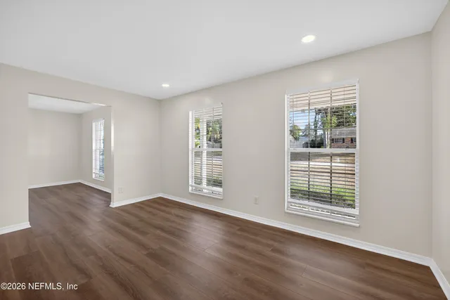a view of an empty room with wooden floor and a window