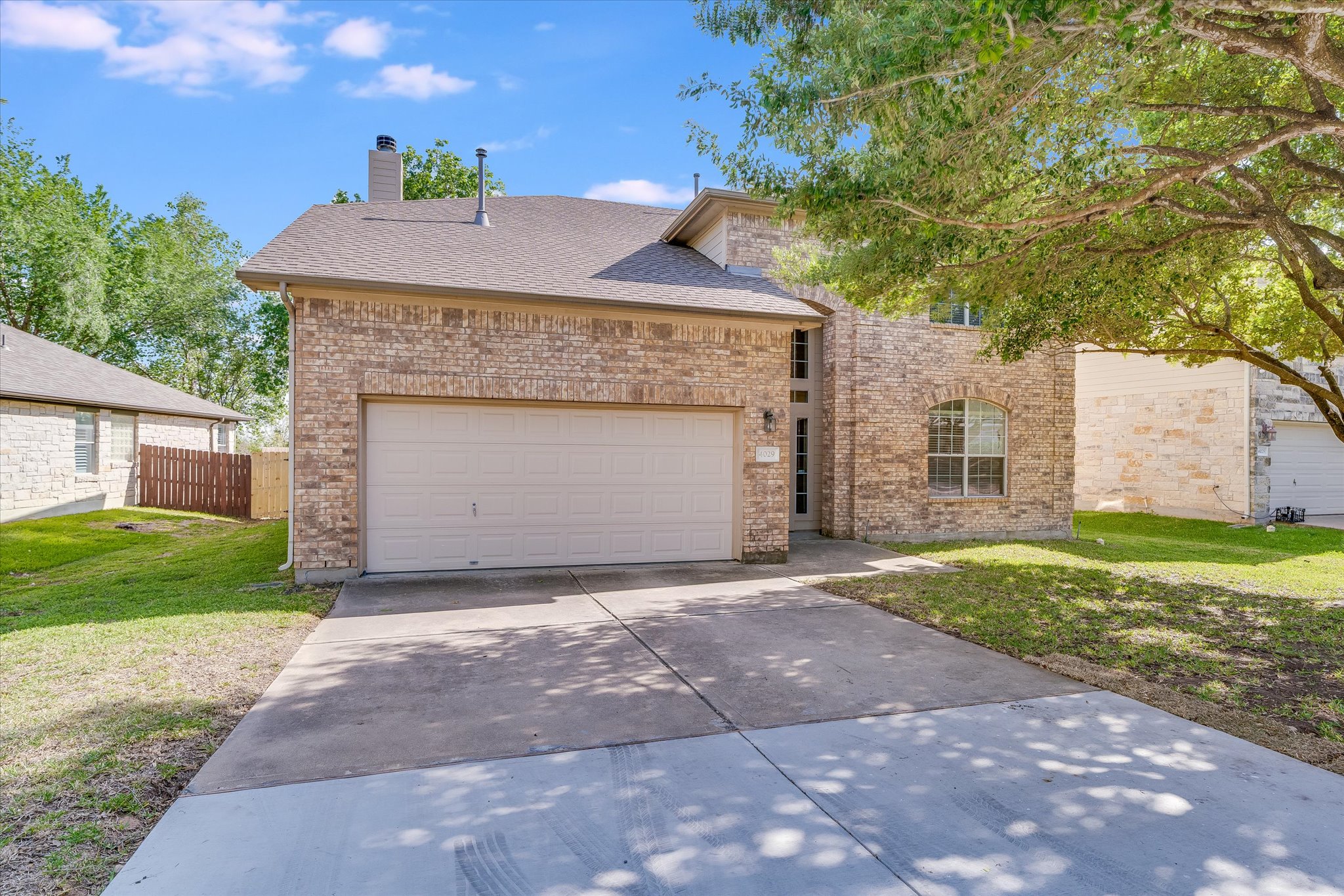 4029 Lake Edge Way Pflugerville, TX 78660 - Photo 2 of 35 View of front of home featuring concrete driveway, an attached garage, brick siding, a chimney, and a shingled roof