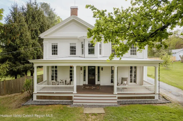 a view of a house with a small yard plants and large trees