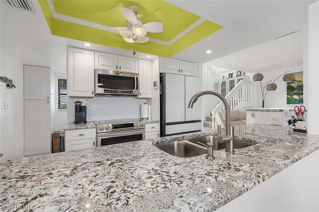 a kitchen with stainless steel appliances granite countertop a sink a stove top oven a refrigerator and a sink