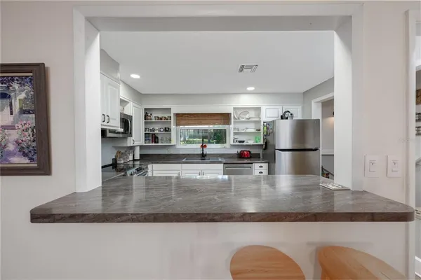 a kitchen with kitchen island a counter top space cabinets stainless steel appliances and a chandelier