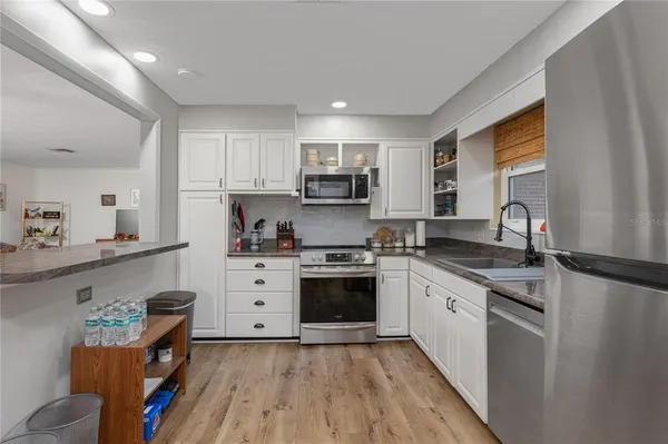a kitchen with granite countertop a sink cabinets stainless steel appliances and a window