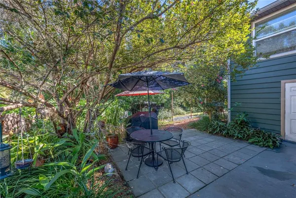 a view of a patio with table and chairs potted plants and large tree