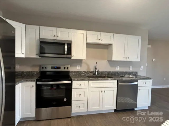 a kitchen with granite countertop white cabinets and stainless steel appliances