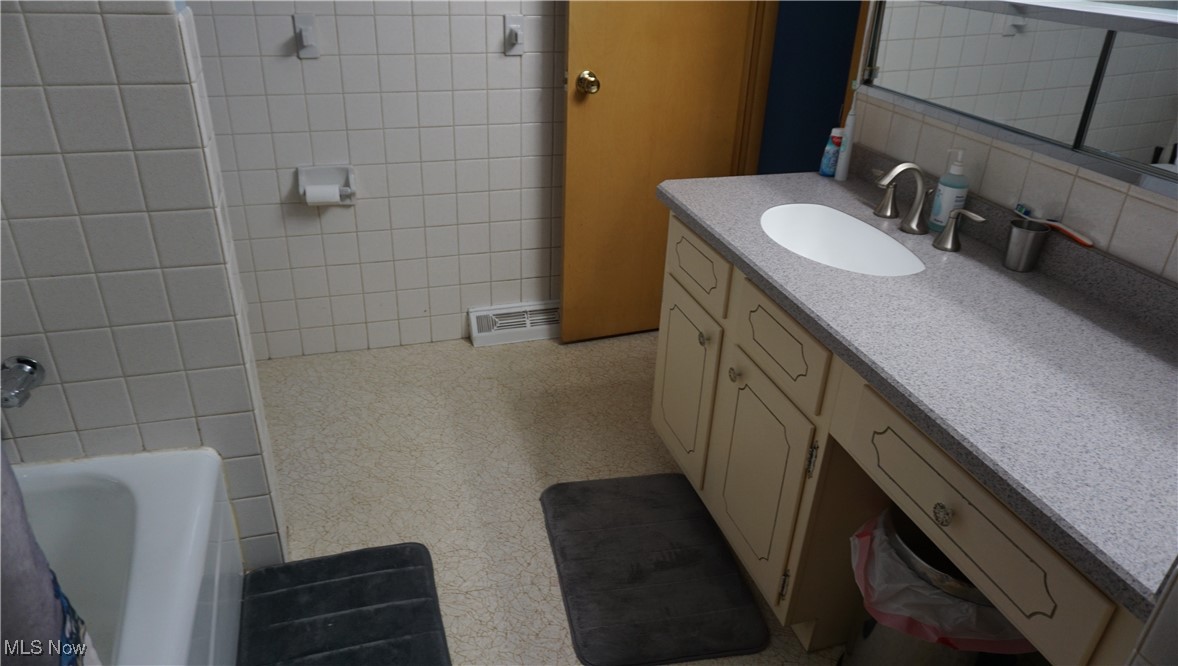 2100 West Pleasant Valley Road Cleveland, OH 44134 - Photo 16 of 30 Bathroom with vanity, a bathtub, tasteful backsplash, tile walls, and a shower