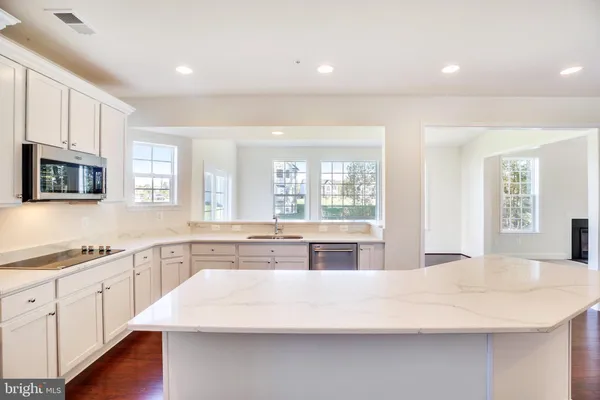 a large kitchen with stainless steel appliances a large counter top a stove and a center island