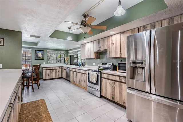 a kitchen with stainless steel appliances granite countertop a sink a stove top oven a chimney cabinets and a dining table