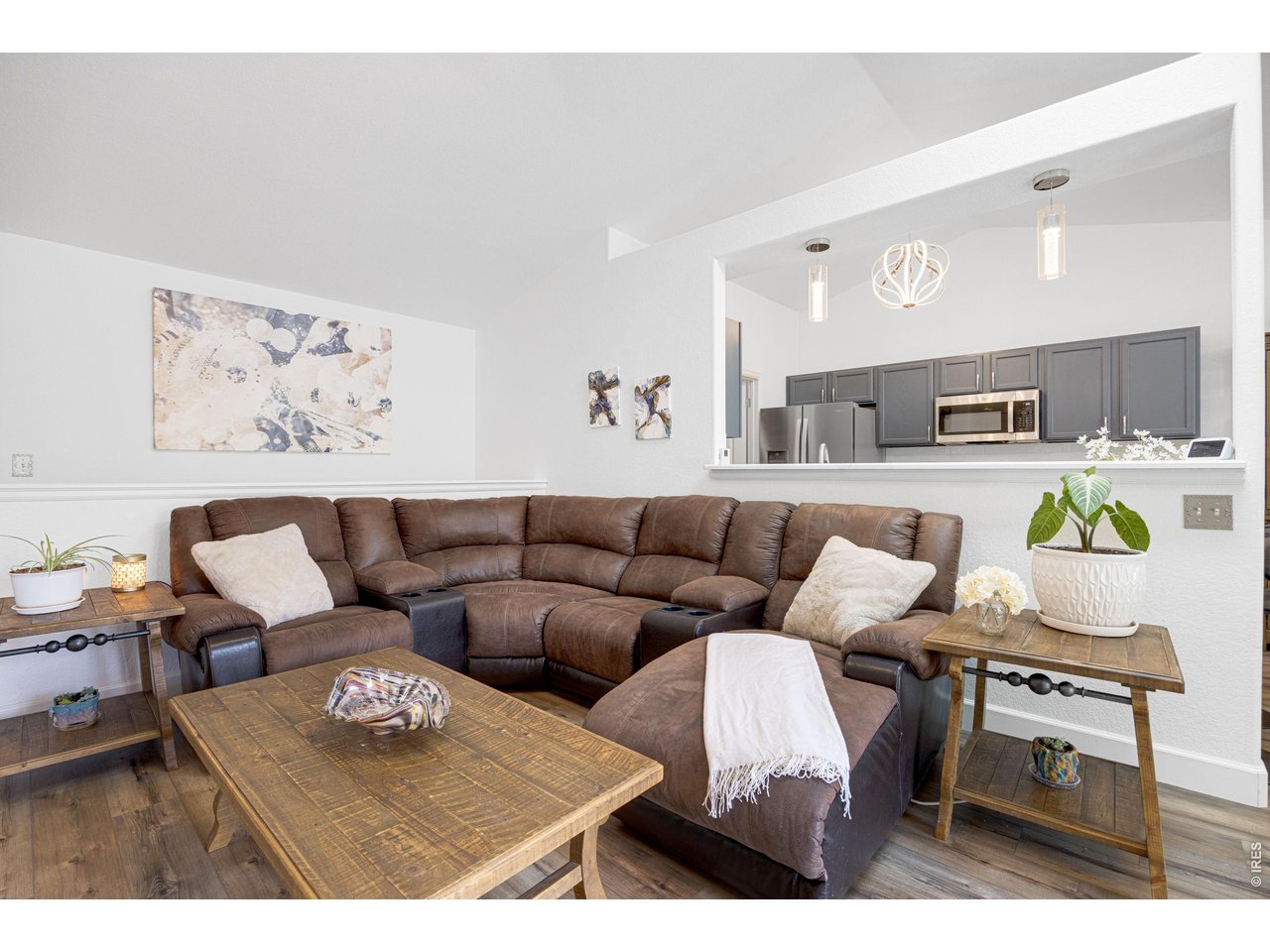148 Beacon Way Windsor, CO 80550 - Photo 5 of 36 Bright and open living room with vaulted ceilings, updated flooring, modern lighting, and a large pass through opening to the kitchen creating an airy, connected layout.