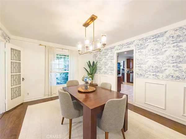 a dining room with chandelier and wooden floor