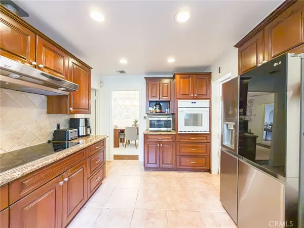 a large kitchen with stainless steel appliances granite countertop a refrigerator and a stove top oven