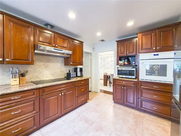 a kitchen with stainless steel appliances granite countertop wooden cabinets a stove top oven a sink and dishwasher with wooden floor