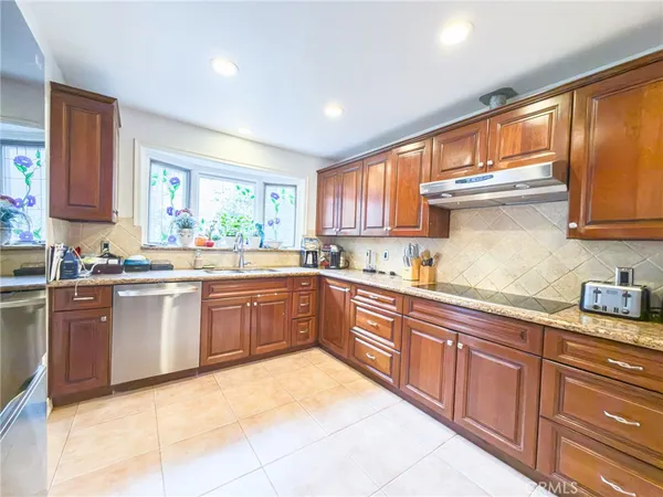a kitchen with stainless steel appliances granite countertop wooden cabinets a window a sink and a counter space