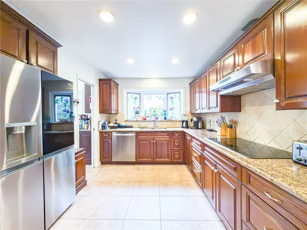 a large kitchen with stainless steel appliances granite countertop a large counter top a stove a sink dishwasher and a refrigerator