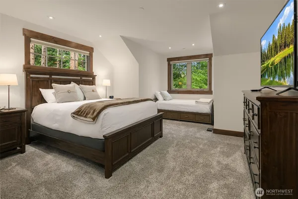 a spacious bedroom with a bed and a flat tv screen