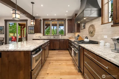 a kitchen with stainless steel appliances granite countertop a sink a stove and a wooden floors