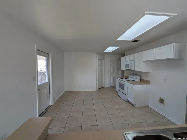 a kitchen with white cabinets and white appliances