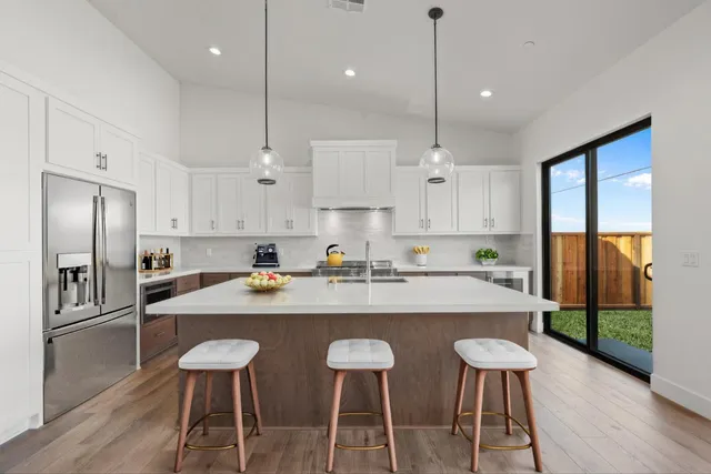 a kitchen with stainless steel appliances granite countertop a sink a stove a refrigerator and island with wooden floor