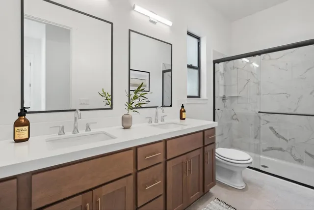 a bathroom with a double vanity sink toilet and a mirror