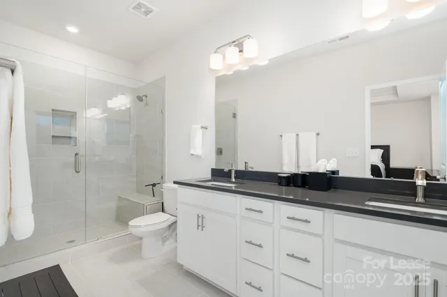 a spacious bathroom with a granite countertop sink a toilet a mirror and shower