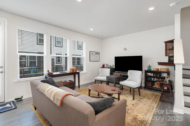 a living room with furniture a flat screen tv and large window