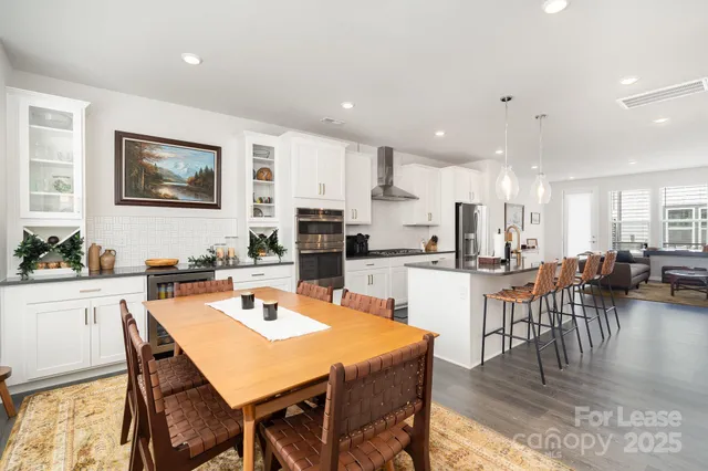a kitchen with a dining table wooden floor stainless steel appliances and cabinets