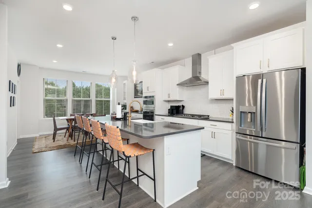 a kitchen with stainless steel appliances a dining table chairs stove refrigerator and cabinets