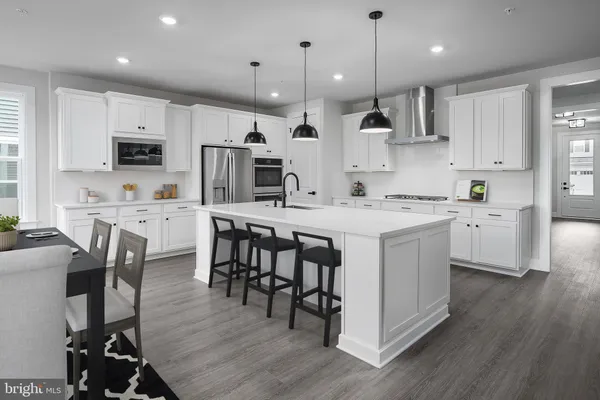 a kitchen that has a lot of cabinets in it with stainless steel appliances a dining table and chairs
