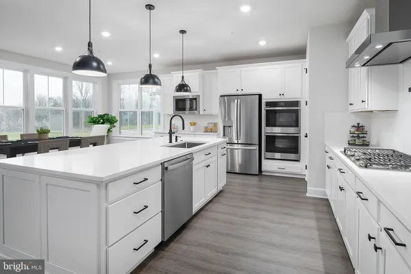 a large white kitchen with lots of counter space and wooden floor