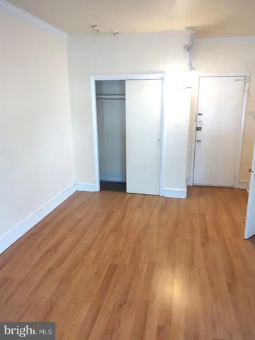 a view of an empty room with wooden floor and a ceiling fan
