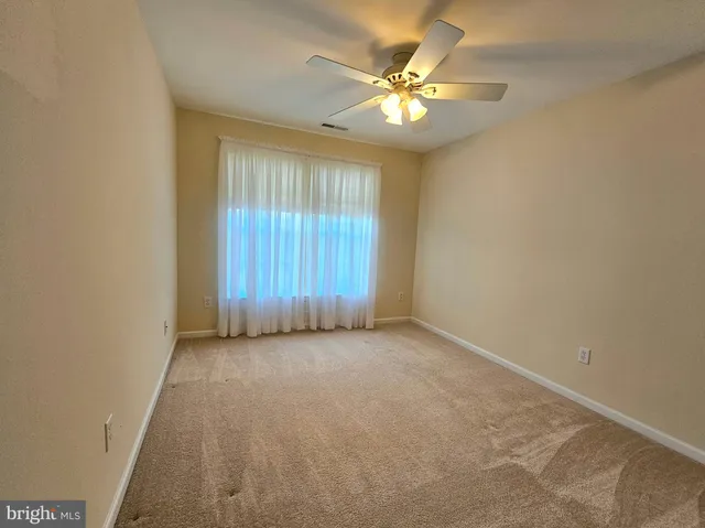 an empty room with a chandelier fan and windows