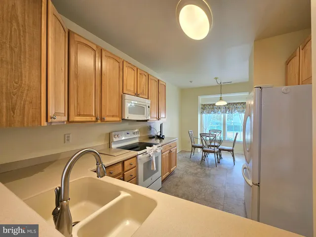 a kitchen with stainless steel appliances granite countertop a stove top oven a sink dishwasher a dining table and chairs with wooden floor