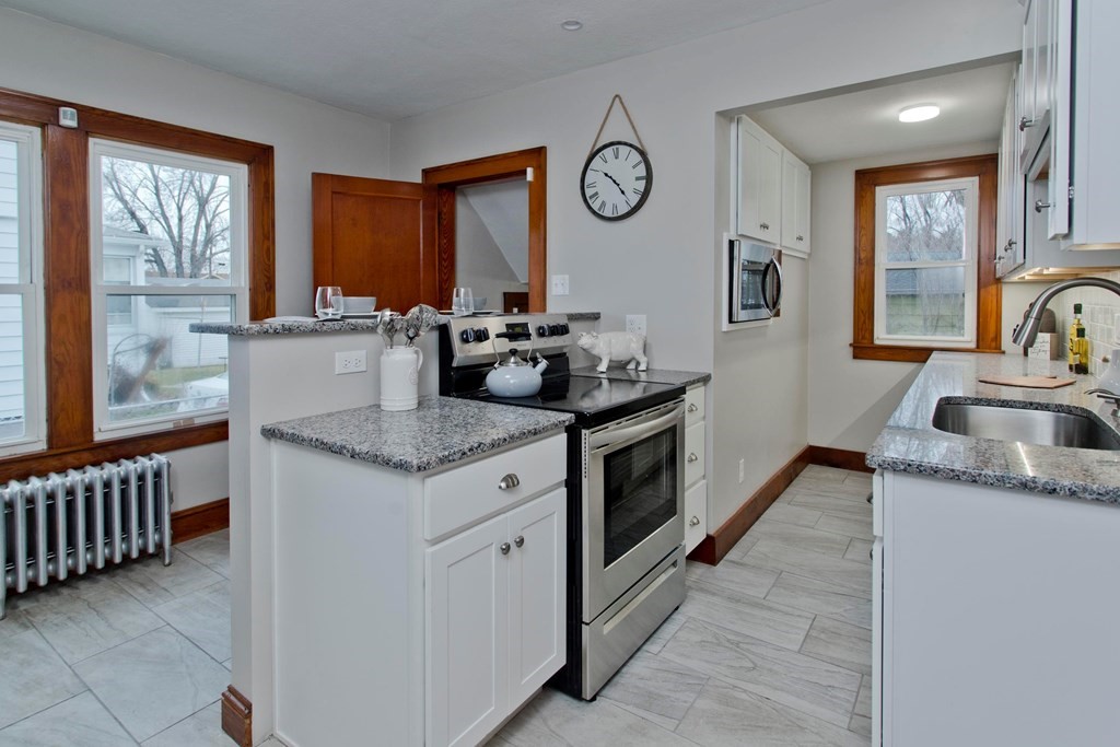 29 Acton Street Springfield, MA 01151 - Photo 6 of 39 a kitchen with granite countertop a sink a stove top oven a clock and a window