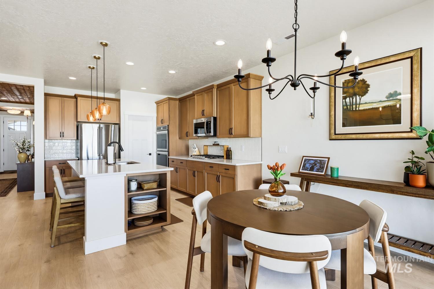 5990 West Ladle Rpds Street Meridian, ID 83646 - Photo 14 of 42 Light wood-finish flooring extending into the kitchen, kitchen island with built-in shelving, stainless steel appliances, and recessed lighting