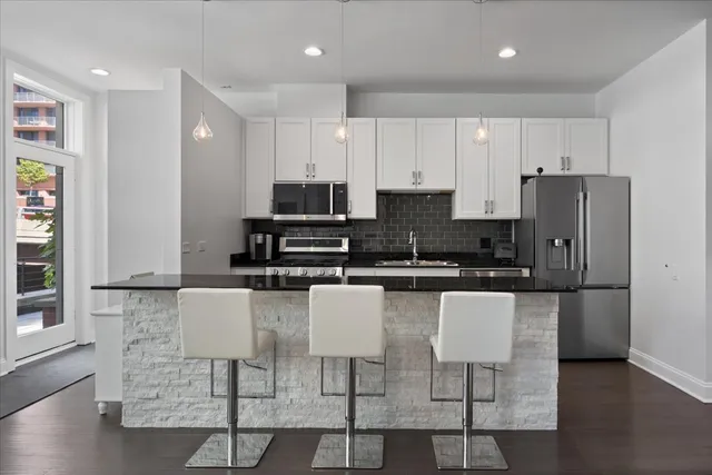 a kitchen with stainless steel appliances granite countertop a refrigerator and a stove top oven
