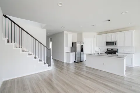 a view of a kitchen with stainless steel appliances a refrigerator and a stove top oven