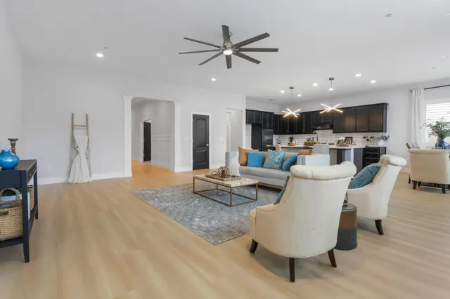a living room with furniture kitchen view and a chandelier